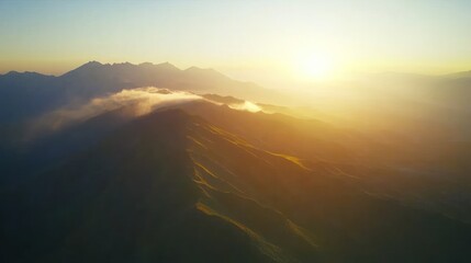 Golden sunrise illuminates a misty mountain range.