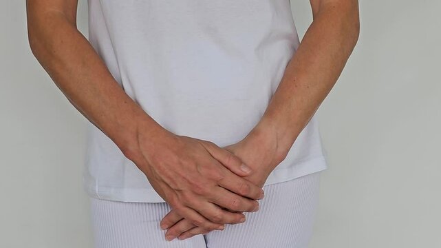 Vaginal urinary incontinence and pain of young woman holding hand to perineum