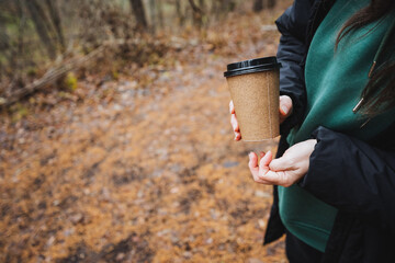 A woman finds solace in a tranquil moment while savoring a warm cup of coffee amidst the serene woods, enveloped by towering trees and soft grass, deeply immersed in the beauty of nature