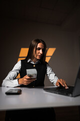 Woman holding a stack of dollars while working on a laptop. Accountant works with money. Concept of...