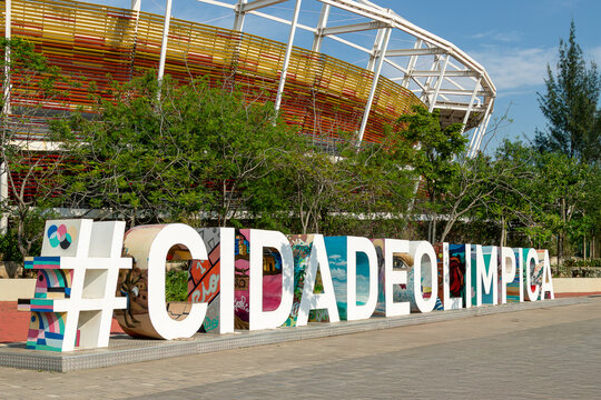 Monumento "#CidadeOl&iacute;mpica" em frente ao Parque Ol&iacute;mpico do Rio de Janeiro e ao fundo estadio 