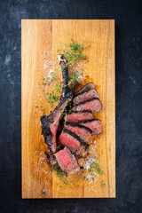 Traditional grilled barbecue dry aged tomahawk beef steak meat with salt and fresh herbs served and...