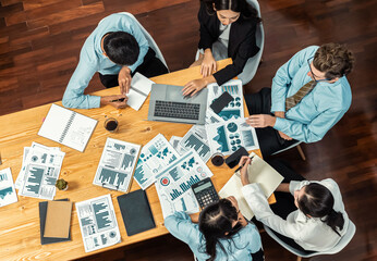 Wide top view of diverse group of business analyst team analyzing financial data report paper on meeting table. Chart and graph dashboard by business intelligence analysis. Meticulous