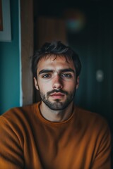 Fototapeta premium A Young Man With a Contemplative Expression Sits in a Cozy Room Adorned With Soft Lighting During Evening Hours