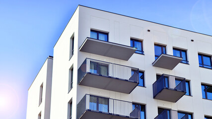 Modern high-rise apartment building  in white, stand tall against a blue sky, exemplifying...