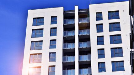 Modern high-rise apartment building  in white, stand tall against a blue sky, exemplifying innovative urban architecture with sleek, angular designs.