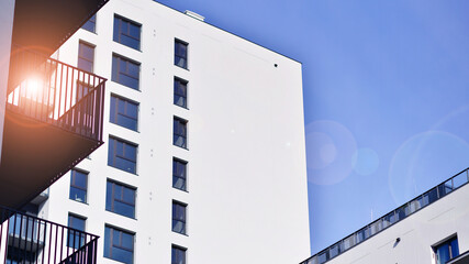Modern high-rise apartment building  in white, stand tall against a blue sky, exemplifying...