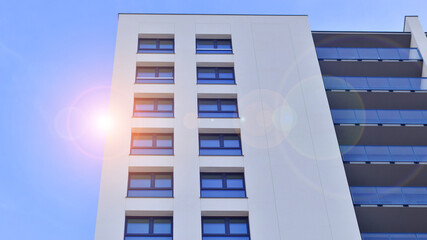 Modern high-rise apartment building  in white, stand tall against a blue sky, exemplifying...
