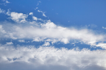 White cumulus and cirrus clouds in the blue sky