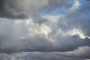 Grey storm clouds on a blue sky, rays of light on grey clouds