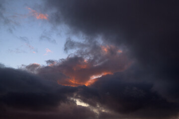 Sky with dark clouds at sunset with some clearings horizontally