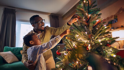 Black father and son setting up a Christmas tree with a living room in the background