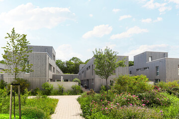 Residential area with ecological and sustainable green residential buildings, low-energy houses with wooden facade, timber construction and green courtyard
