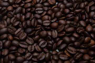 A pile of coffee beans. All stacked together, waiting to be ground into a delicious cup of coffee. A close-up shot of roasted coffee beans. Different types of delicious coffee beans.