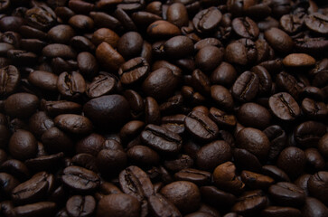A pile of coffee beans. All stacked together, waiting to be ground into a delicious cup of coffee. A close-up shot of roasted coffee beans. Different types of delicious coffee beans.