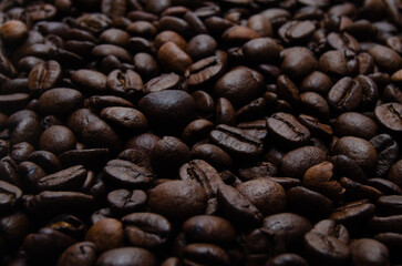 A pile of coffee beans. All stacked together, waiting to be ground into a delicious cup of coffee. A close-up shot of roasted coffee beans. Different types of delicious coffee beans.