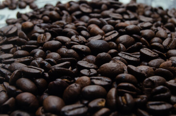 A pile of coffee beans. All stacked together, waiting to be ground into a delicious cup of coffee. A close-up shot of roasted coffee beans. Different types of delicious coffee beans.