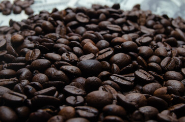 A pile of coffee beans. All stacked together, waiting to be ground into a delicious cup of coffee. A close-up shot of roasted coffee beans. Different types of delicious coffee beans.