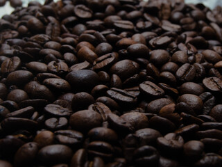 A pile of coffee beans. All stacked together, waiting to be ground into a delicious cup of coffee. A close-up shot of roasted coffee beans. Different types of delicious coffee beans.