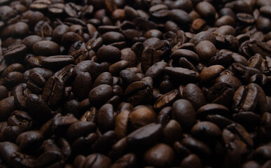 A pile of coffee beans. All stacked together, waiting to be ground into a delicious cup of coffee. A close-up shot of roasted coffee beans. Different types of delicious coffee beans.