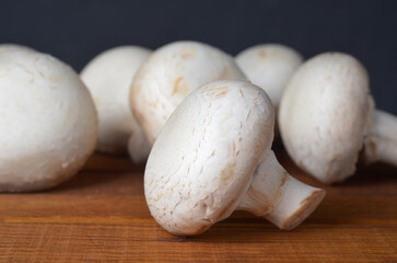 Fresh champignon mushrooms close-up on a kitchen wooden board, frontal view, detail, cooking,...