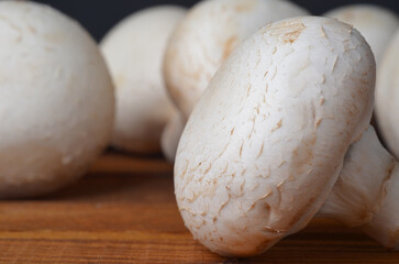Fresh champignon mushrooms close-up on a kitchen wooden board, frontal view, detail, cooking, healthy food, diet