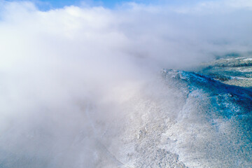 drone aerial view of a mountain with snow and mist, winter background concept