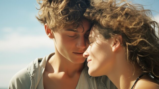 Young couple embracing on sunny beach with windswept hair