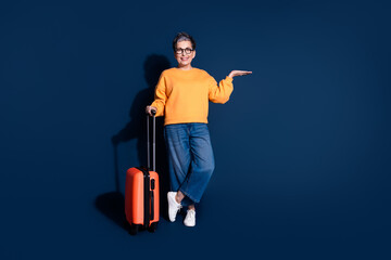 Full size photo of pretty senior female hold empty space travel suitcase wear trendy yellow outfit...