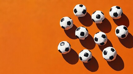 Obraz premium A group of black and white soccer balls on an orange surface with a shadow of them in the center of the picture
