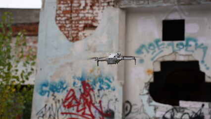 A drone in the sky next to a ruined, abandoned building