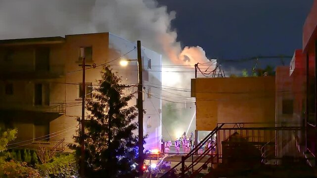 Video shot of a burning building being extinguished by firefighters in the city