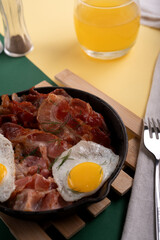 photograph, ,breakfast, pan, bacon, egg, sunny, side, herb, glass, orange, juice, fork, knife, set, cloth, napkin, salt,