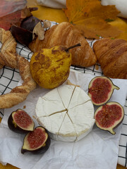 Close-up of an autumn picnic on a checkered blanket featuring cheese, pear, and fig.