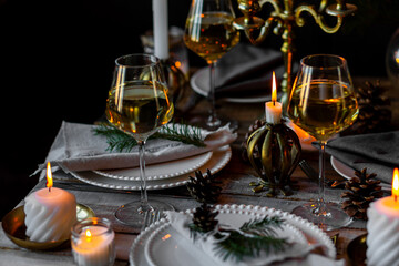 Elegant decor for Christmas family dinner. Center piece with burning candles, vintage chandelier. Zero waste eco-friendly reusable home decoration, fir tree branches. Cozy atmosphere, wooden furniture