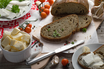 Rustic Bread with Feta, Parsley, and Cherry Tomatoes, Fresh Ingredients on Wooden Board. Feta-Topped Bread with Herbs and Tomatoes, Rustic Kitchen Setup.