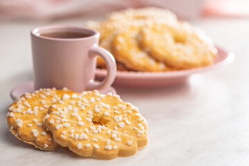 Sweet cookies in the shape of a flower. Tasty biscuits and cup of tea on white table.