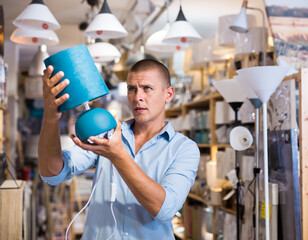 Portrait of young man customer buying trendy lamp in modern furniture showroom