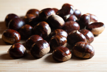 Autumn fresh raw shiny chestnuts on a wooden table