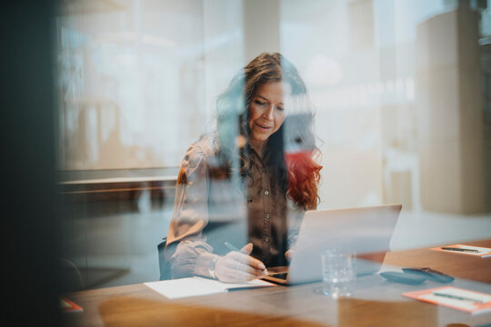 Mature businesswoman using laptop while sitting at desk in office