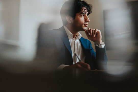 Young businessman sitting with hand on chin at office