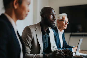 Mature bald businessman sitting with male and female colleague while working in office