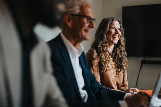 Happy businesswoman sitting by male colleague at office