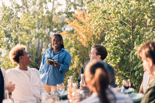 Smiling woman enjoying with group of friends in dinner party at back yard