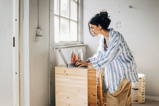 Focused female designer working on laptop at workshop
