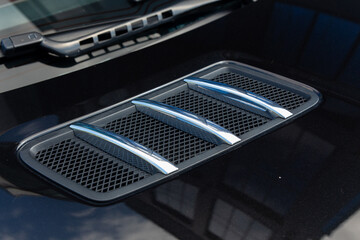 Close-up of chrome-plated air intakes on the hood of a black car