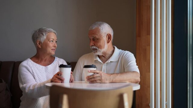 Portrait of retired couple with gray hair enjoying coffee together in cozy cafe, radiating love and contentment, cherishing every moment of golden years. Concept of active aging and happy retirement.