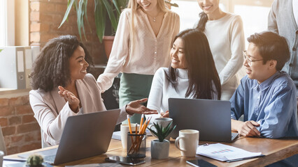 Close up of professional afro woman sharing business ideas with international colleagues in office