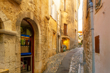 Obraz premium One of the many narrow cobblestone walkways, streets and paths of shops and cafes in the hilltop medieval village of Saint-Paul de Vence, France.