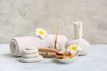 Beautiful composition with herbal bag, towel, bowl of sea salt, spa stones, plumeria flowers and...